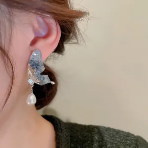 Boucles d'oreilles papillon avec cristaux gris-bleu et perles portées par un mannequin
