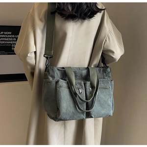 Detail view of large corduroy crossbody bag with dual zip pockets on model back