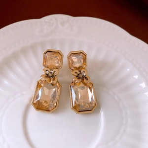 Macro shot of vintage gold earrings with champagne crystals on a white ceramic plate