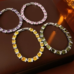 Detalle de pulseras de circonita de colores con corte cuadrado sobre cuero marrón