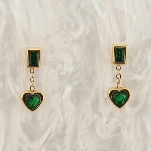 Detailed macro of 18K gold plated earrings with heart and square green zircon stones