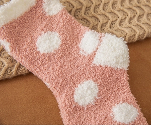 Close-up of soft pink and white polka dot coral fleece socks with thick plush texture