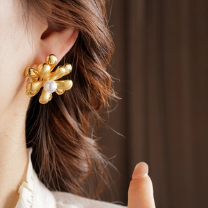 Detail of 18k gold plated flower earring with central pearl on model wearing