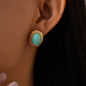 Detailed close-up of vintage gold stud earring with green turquoise stone on model