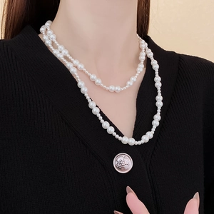 Détail d'un collier de perles double rang avec fermoir à bascule sur pull noir