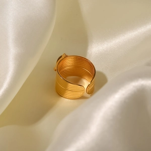 Gold wide-band stainless steel adjustable ring on beige silk background with textured finish