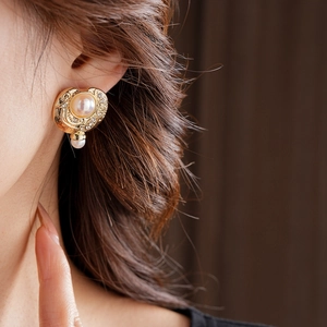 Gros plan de boucles d'oreilles vintage dorées avec perles et cristaux sur l'oreille