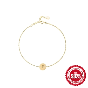 Vista macro de pulsera de plata S925 bañada en oro con medallón grabado letra F