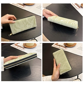 Detail view of long light green zip wallet with crinkled texture fabric and zip closure