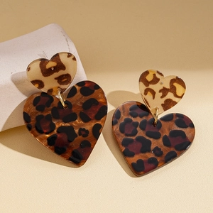 Detail view of acrylic leopard print heart earrings on a minimalist plaster prop