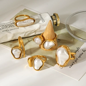 Close-up of golden irregular baroque pearl rings set on a rustic wooden stand