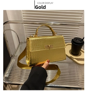 Detail of gold crocodile texture handbag with metal rotary lock and top handle