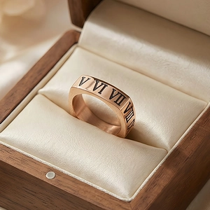 Détail d'une bague en or rose avec chiffres romains dans un écrin à bijoux en bois