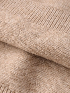 Close-up of soft camel knit fabric with detailed ribbed edge and fine cashmere texture