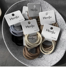Detailed view of elastic seamless hair ties in neutral tones on a textured display
