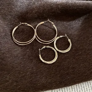 Retro golden interlaced hoop earrings with textured finish on warm vintage background