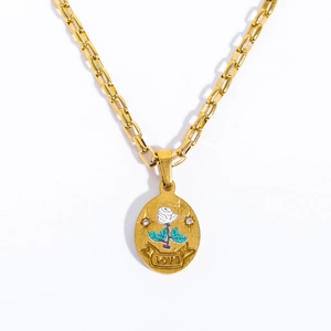 Macro detail of gold oval pendant featuring a white rose, green leaves, and LOVE engraving