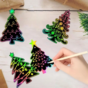 DIY Christmas scratch art kits with rainbow tree designs and wooden stylus on a wooden desk
