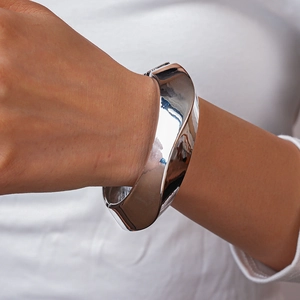 Close-up of polished silver wide twisted metal bangle on wrist with minimalist design