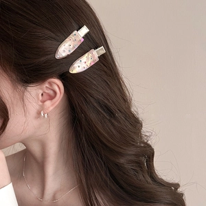 Detail view of pearlescent water drop hair clips with rhinestones on wavy hair