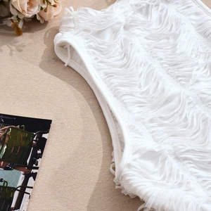 Dettaglio ravvicinato delle frange bianche e della trama del tessuto plissettato stile boho