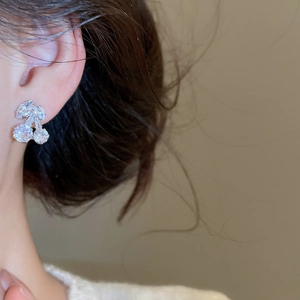 Close-up of cherry stud earrings with zircon crystals and silver finish on a model