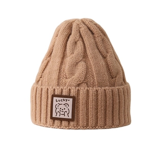 Thick knit winter beanie for kids featuring a cable pattern and cute lucky bear patch