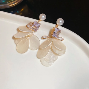 Detailed close-up of long tassel earrings with purple gems and shell-style sequins