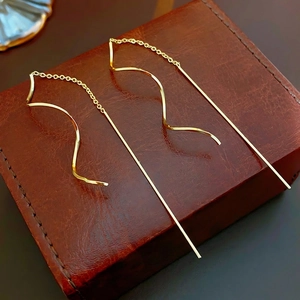 Boucles d'oreilles pendantes vagues dorées sur une boîte à bijoux en cuir marron vintage