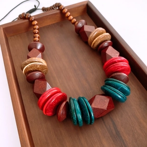 Detailed close-up of Bohemian wood and resin beaded necklace on a dark wooden tray