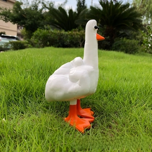 Detail of white resin duck statue with middle finger gesture on outdoor green grass