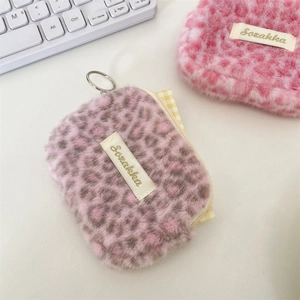 Dettaglio di portamonete in peluche leopardato con cerniere in metallo e texture morbida