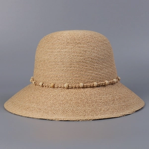 Detail eines beigen Raffia-Sonnenhuts mit dekorativem Holzperlen- und Seilbandbesatz