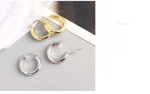 Polished 18K gold and silver hoop earrings with pin closure on a soft grey background