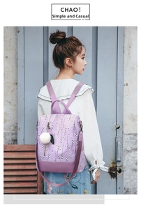 Close-up of purple floral backpack with fluffy ball charm on a textured wooden door