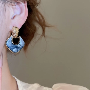 Close-up of vintage acrylic drop earrings with gold hammered texture and blue marble effect