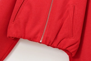 Detail showing the red bomber jacket's silver zipper and elastic waistband hem