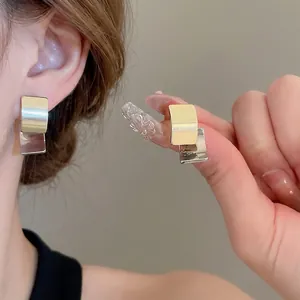 Square two-tone gold and silver metal stud earrings in a minimalist geometric design