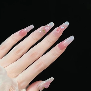 Detail of pink ombré press-on nails with 3D floral accents and pearls on coffin shape