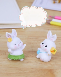 Detailed view of two cute pink resin rabbit figurines on a wooden desk with office props