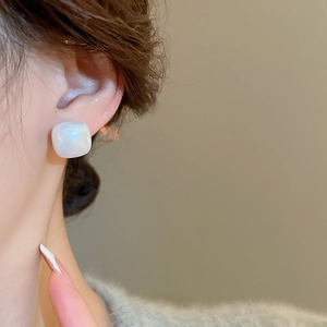 Macro detail of square pearl stud earring with soft luster on a female model's ear