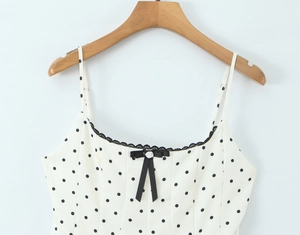Detail of white polka dot camisole with black lace trim and bow on wooden hanger