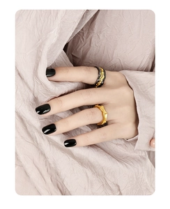 Detail of twisted silver rings with relief texture on model hand with black nails