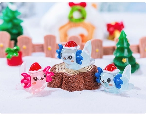 Close-up of three colorful axolotl figurines with Christmas hats in a snow scene