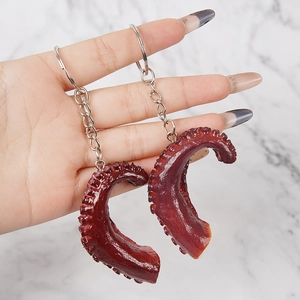 Realistische PVC octopus tentakel sleutelhangers in de hand op een marmeren achtergrond
