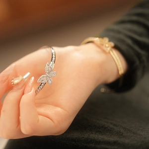 Detail of gold and silver butterfly cuff bracelets with cubic zirconia on a wrist