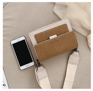 Flat lay of retro bicolor crossbody bag with wide strap and branded flap detail