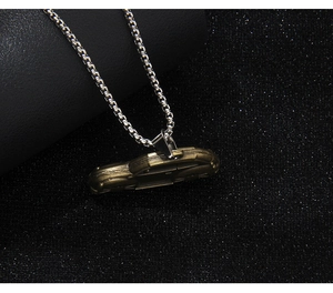 Close-up of vintage bronze car pendant necklace on a textured black surface