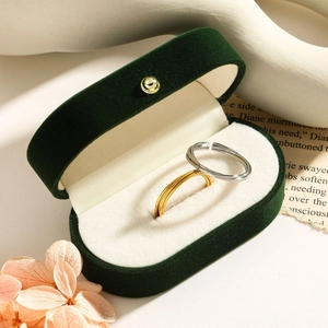 Close-up of gold and silver twisted wheat rings in a dark green velvet jewelry box