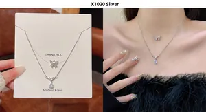 Detail view of double-layer silver bow necklace and teardrop crystal pendant on model